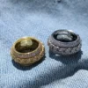 Gold and silver Cuban spinner rings displayed on denim