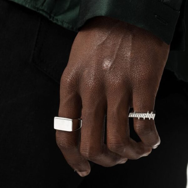 Silver logo ring and chunky square ring against dark backdrop