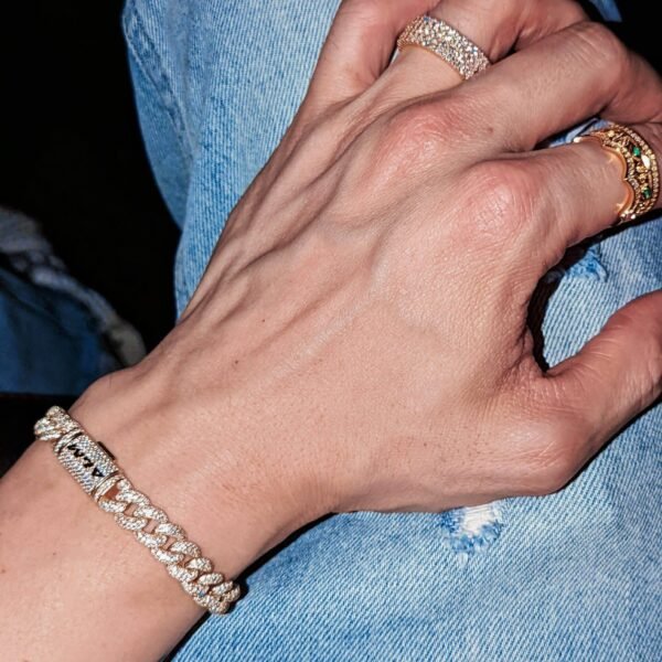 18K gold diamond-encrusted Cuban link bracelet and rings styled against light denim background