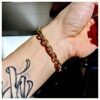 Gold diamond gridlock bracelet shown on tattooed wrist with natural lighting casting shadows