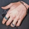 Hand wearing emerald ring and silver pyramid ring with matching bracelet