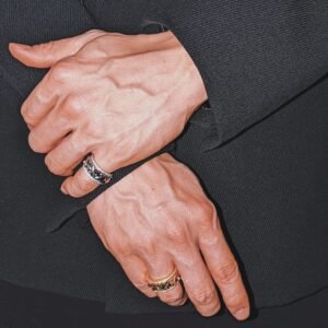 Mixed metal pyramid stud crown rings shown on hands against black fabric Filename: almighty-pyramid-stud-ring-styling
