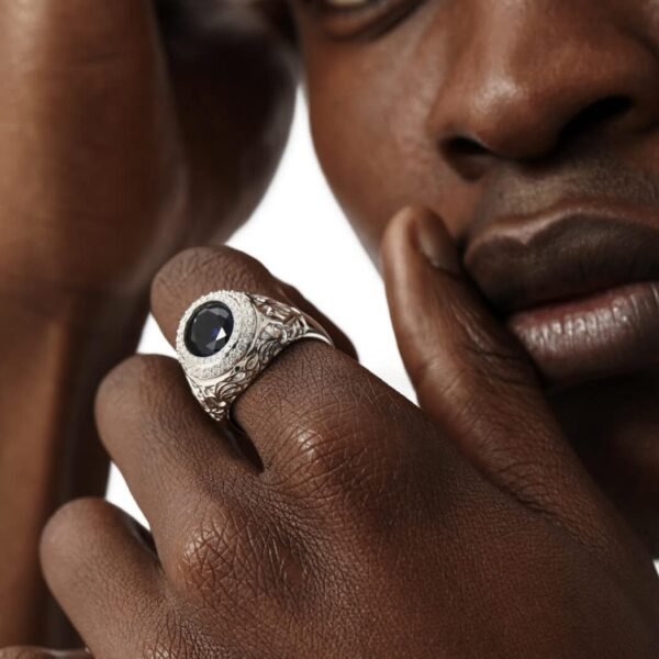 White gold sapphire ring with diamond halo and engraved details shown in close-up on dark-skinned model