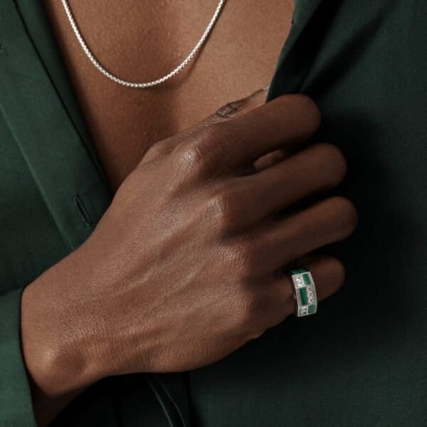 Hand wearing silver ring with emerald accents against green silk shirt