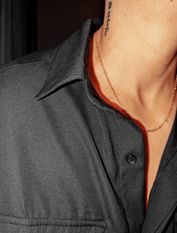 Close-up of gold cable link chain necklace against black shirt