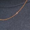 Close-up detail of gold cable link chain against black ribbed fabric