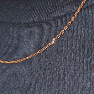 Close-up detail of gold cable link chain against black ribbed fabric