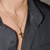 Gold plated polished cross pendant reverse side on fine chain with black shirt