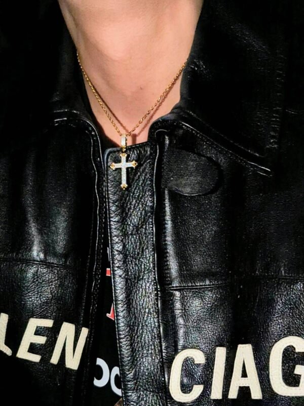 Gold plated cross pendant with diamond accents on chain, worn with black leather jacket