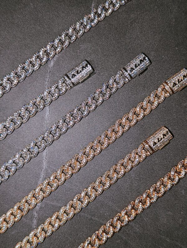 Multiple diamond-encrusted cuban link chains in white gold and 18k gold displayed on dark surface