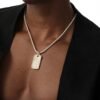 Gold dog tag pendant with crystal pattern on white gold tennis chain, styled with black blazer