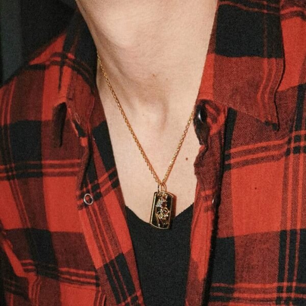 Gold-tone dog tag pendant necklace styled with red plaid flannel and black t-shirt