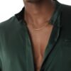 Gold cable link chain on model wearing dark green shirt