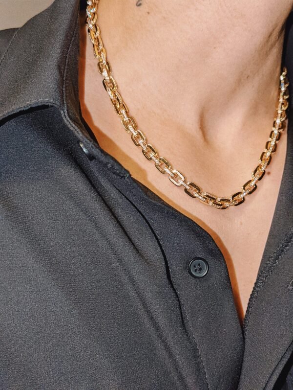 Gold-plated chain necklace with cubic zirconia gridlock pattern against black shirt