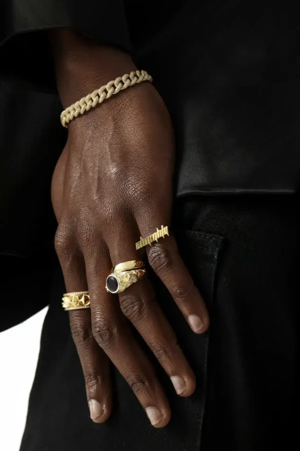 Multiple gold rings paired with curb chain bracelet on dark skin tone