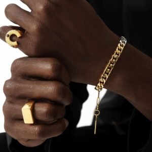Gold rings paired with Cuban link bracelet, worn on dark skin against black clothing