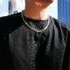 White gold gridlock chain necklace styled with black t-shirt against urban backdrop