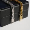 Gold and silver gridlock bracelets with pavé stone detail against black box