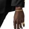 Two-tone curb chain bracelet and gold horseshoe ring against black formal wear