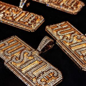 Gold plated HUSTLE pendants with full cubic zirconia setting on black background