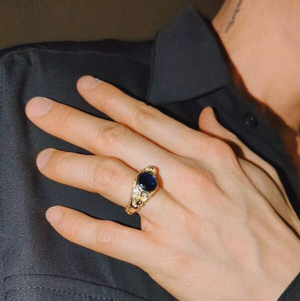 Gold leopard ring with blue sapphire worn with black shirt, showing sculptural animal details