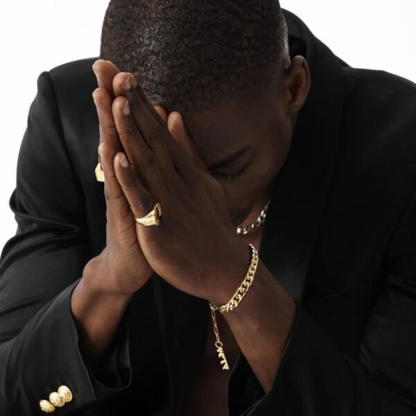 Model wearing gold lucky horseshoe rings and mixed metal chain bracelet in prayer pose