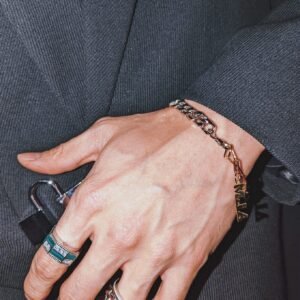 Hand modeling a gold chain bracelet paired with silver pyramid ring and green malachite ring