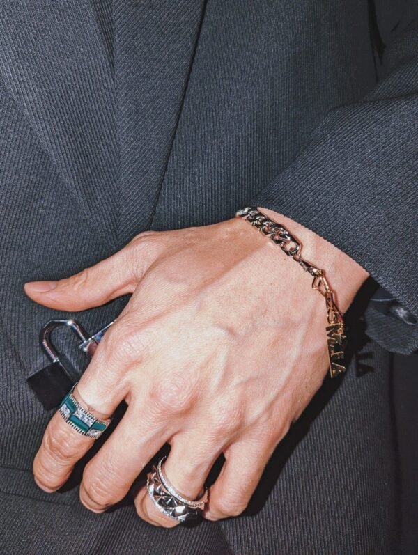 Hand modeling a gold chain bracelet paired with silver pyramid ring and green malachite ring