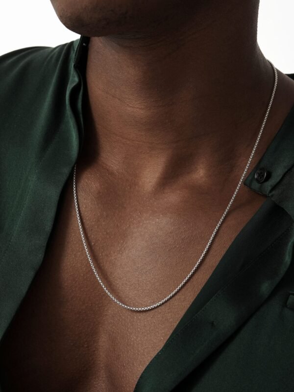 Close-up of white gold round box chain necklace with green shirt styling