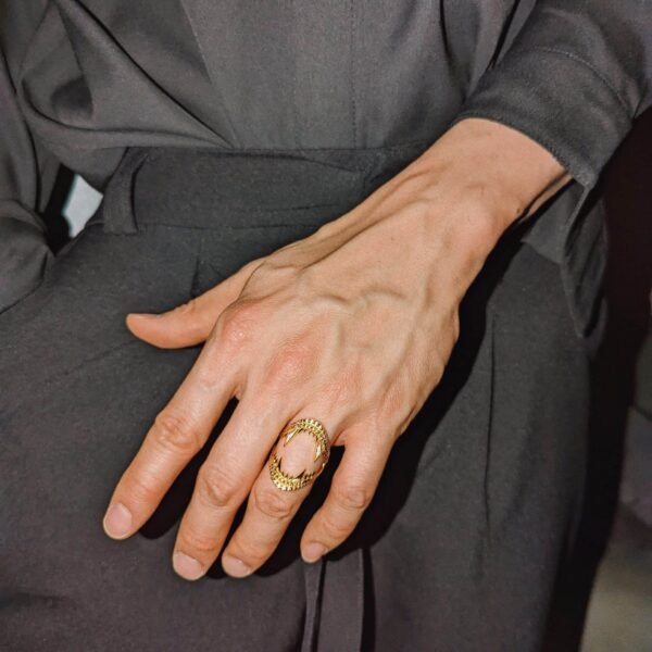 Gold ring with shark jaw design worn with black outfit, creating an oval negative space