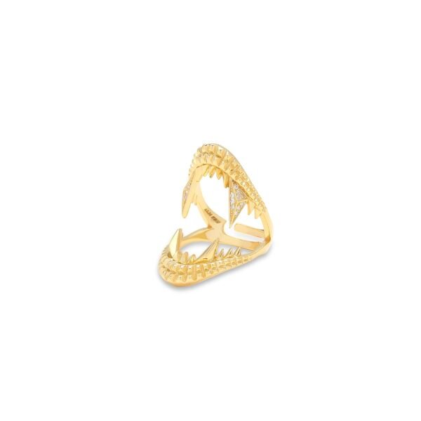 Side angle view of gold-plated shark jaw ring with textured edges and diamond accents on white background