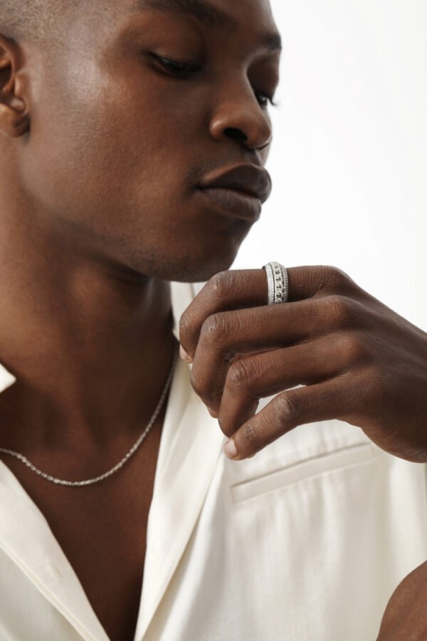 Silver eternity ring and chain necklace against white fabric