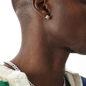 Profile view of silver pyramid stud earring and silver Cuban chain necklace on model