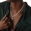 Silver tennis chain necklace with crystal cross pendant worn with dark green silk shirt