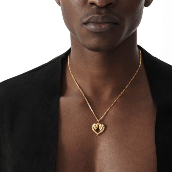 Gold plated skull heart pendant on anchor chain necklace against black blazer backdrop