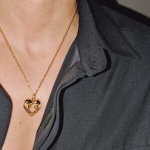Gold plated heart pendant with skull design worn with black shirt