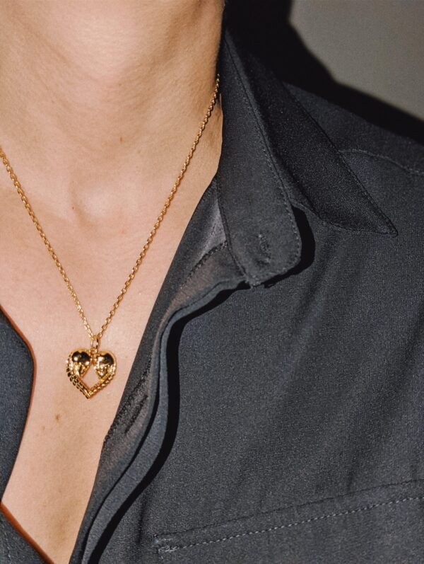 Gold plated heart pendant with skull design worn with black shirt