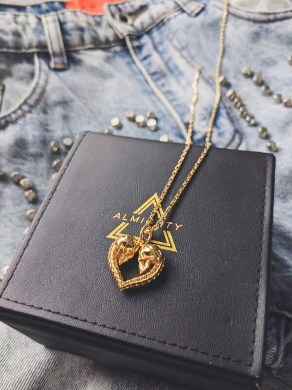 Gold plated skull heart pendant on branded jewelry box with denim background