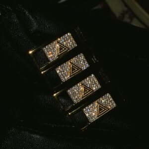 Four gold sneaker crowns with diamond-like stones on dark background
