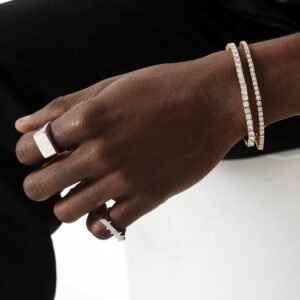 White gold square signet ring paired with gold diamond tennis bracelets on dark skin against black and white background