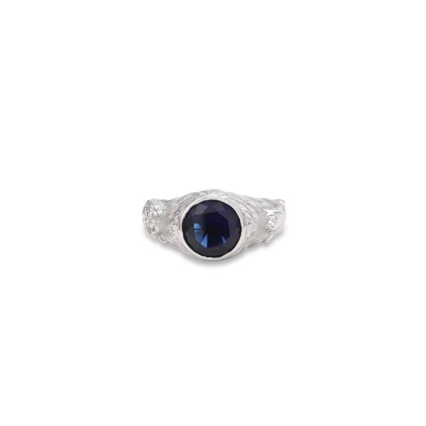 Silver tiger ring with deep blue sapphire center stone shown face-forward on white background