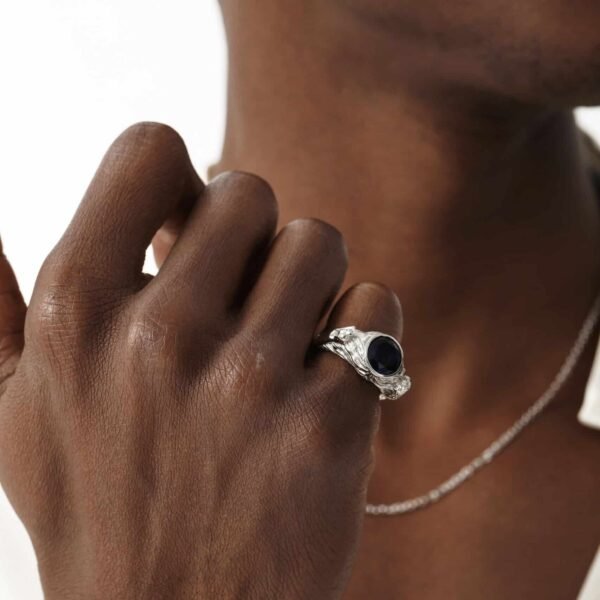 Silver tiger ring with blue sapphire worn with delicate chain necklace on dark skin