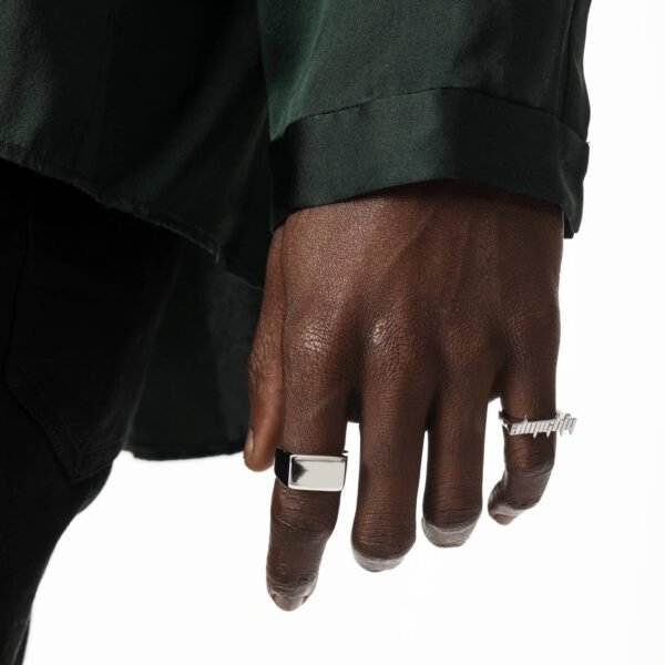 White gold square signet ring and text ring worn with emerald green blazer on dark skin